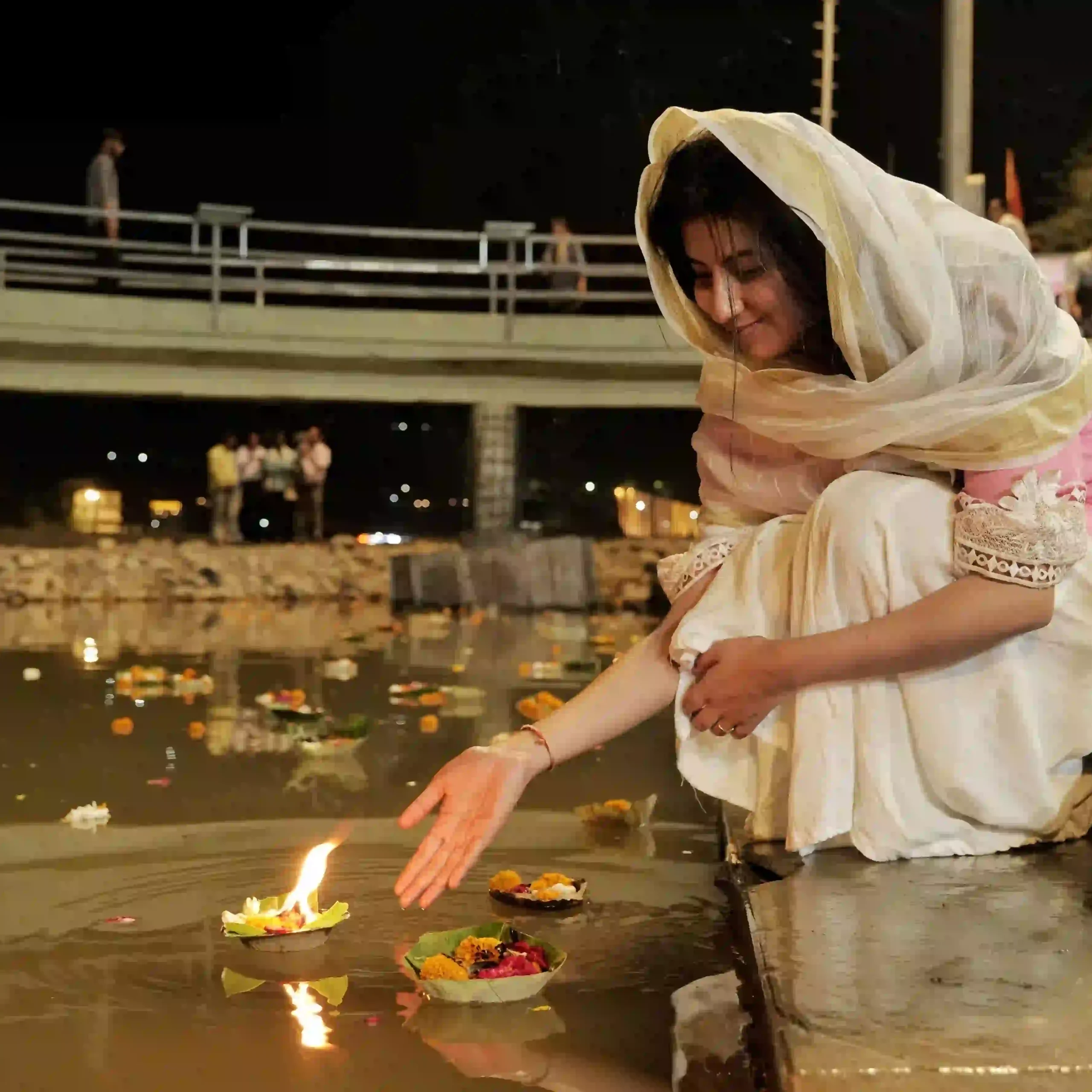 Indian woman floating a diya at a river ghat during a meaningful spiritual travel experience